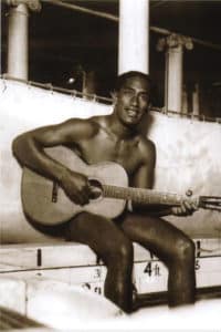 Duke Kahanamoku playing a guitar by the poolside Chicago 1918